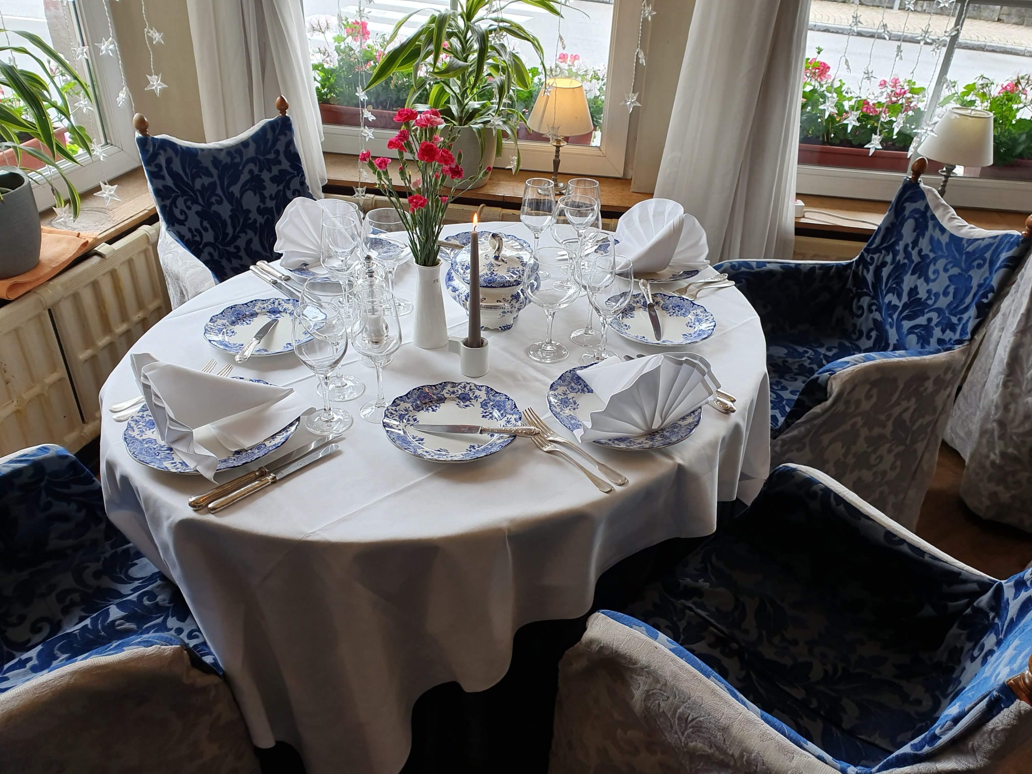 Table ronde dressée avec porcelaine bleue et blanche, fleurs et bougies au Restaurant Bonhomme